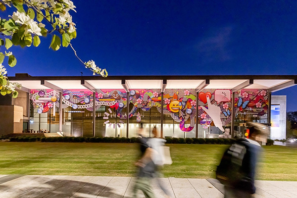 An image of the facade of the University of Queensland Art Museum wrapped in vinyl panels. Artwork made by Kate Geck and features glitch, emoji, digital detritus at huge scale. The facade had augmented reality markers with embdedded guided meditations.