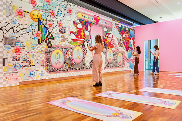 An instalation image of the augmented reality artwork by Kate Geck called rlx:tech defrag popup, commissioned by the University of Queensland Art Museum in 2021. A large vinyl wrapped wall contains augmented reality markers that pop guided meditations which aim to increase your productivity.