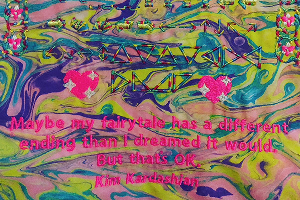 Close up detail image of embroidered textile with a quote from Kim Kardashian and webdings by artist Kate Geck exhibited for Melbourne Fashion Week 2019